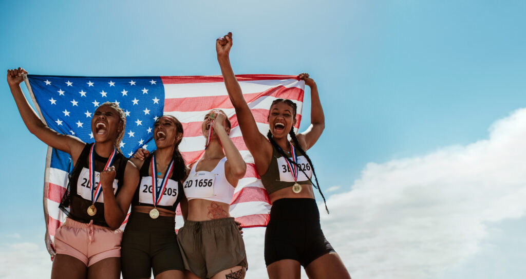 american female athletes celebrating a win holding flag