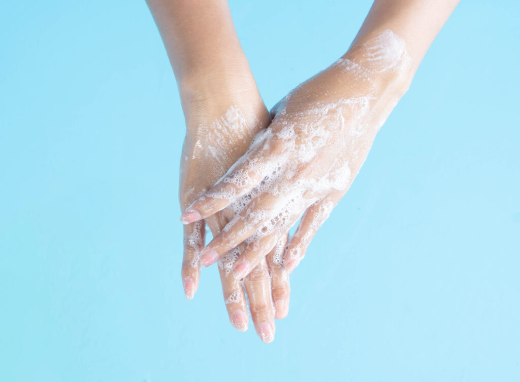 closeup woman's hand washing with soap on blue background, healt