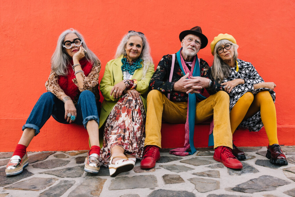 carefree elderly friends sitting against a red wall
