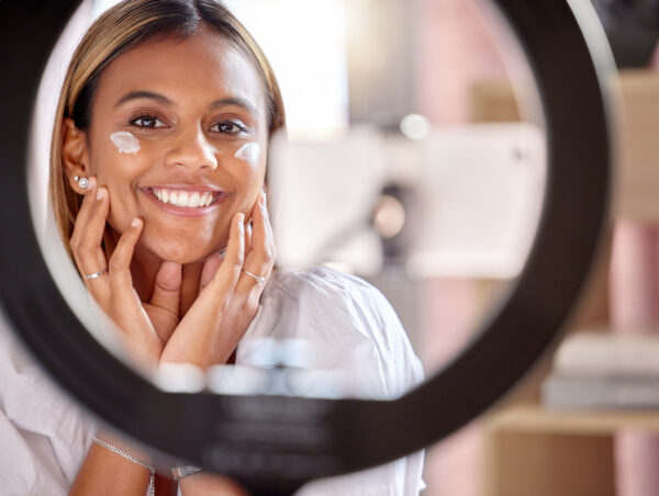 black woman influencer, skincare cream and streaming tutorial for portrait, smile and beauty on social media. gen z girl, digital cosmetic expert or online makeup education for face product on web