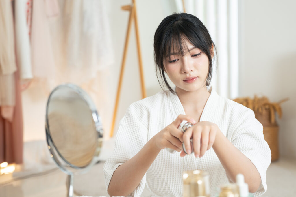 calm morning skincare routine, asian woman in white robe, natural light beauty, minimal vanity, soft focus mirror, gentle moisturizer application creates serene self care mood and healthy glow
