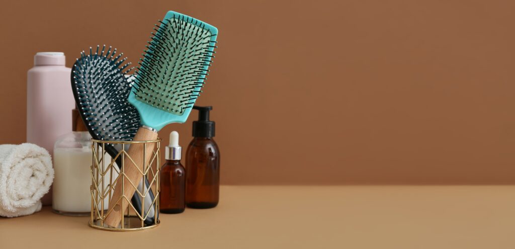 hair care products and brushes for beauty routine, self care, and personal grooming on brown background