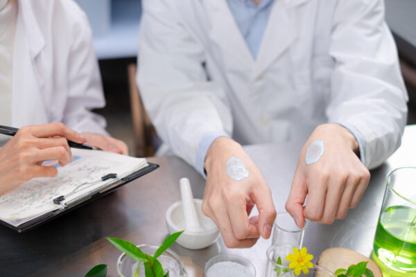 close up hand's of scientist is comparing the result of lotion in beauty laboratory. concept of cosmetic researcher. eco and organic skin care product experiment.